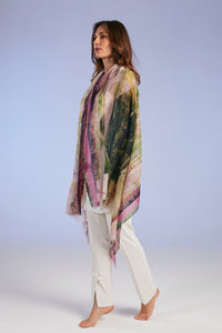 Woman wearing a colorful scarf and white pants on a light gray background