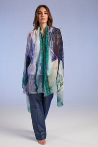 Woman wearing a colorful scarf and pants on a plain background